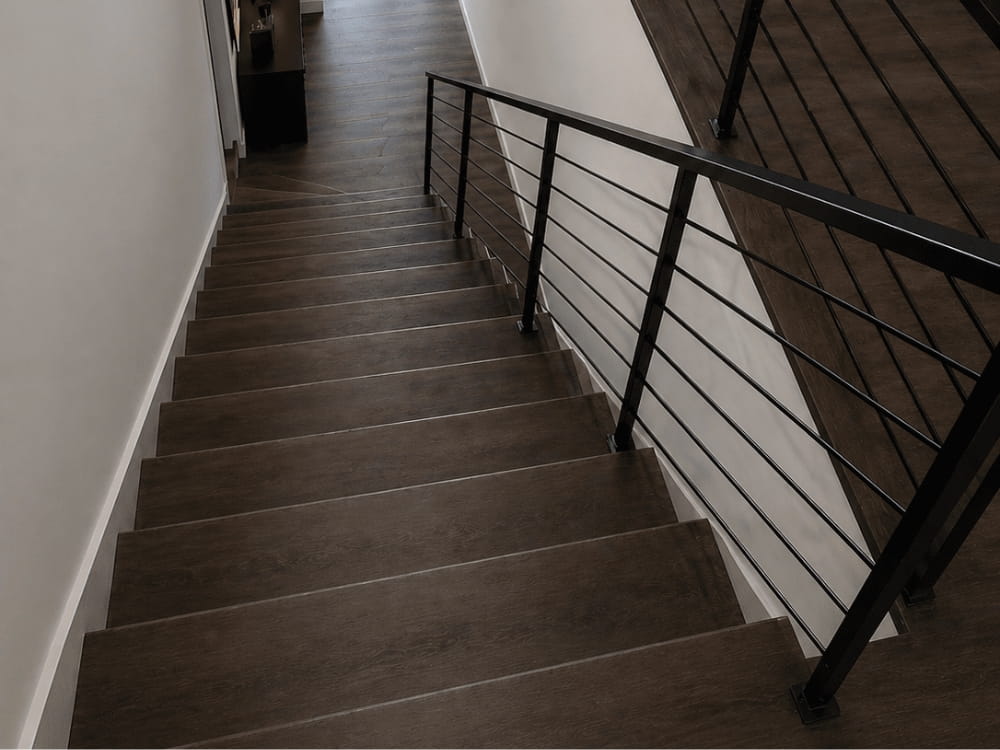 Moderne pvc traprenovatie met donkere houtlook en zwart stalen trapleuning
