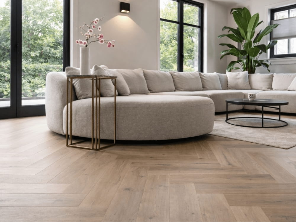 Warme PVC visgraatvloer onder een royale beige hoekbank in een licht en modern wooninterieur